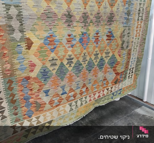 שטיח צבעוני תלוי לייבוש על מתלה מתכת